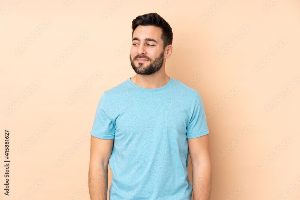 Caucasian handsome man isolated on beige background having doubts while looking side Caucasian handsome man isolated on beige background having doubts while looking side