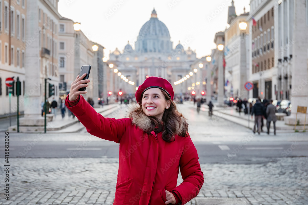 Selfie of young woman in Rome, Italy. Girl in red dress and red beret takes a selfie with the background of St. Peter's Basilica in the Vatican. 