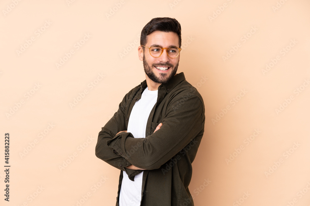 Caucasian handsome man isolated on beige background looking to the side and smiling Caucasian handsome man isolated on beige background looking to the side and smiling