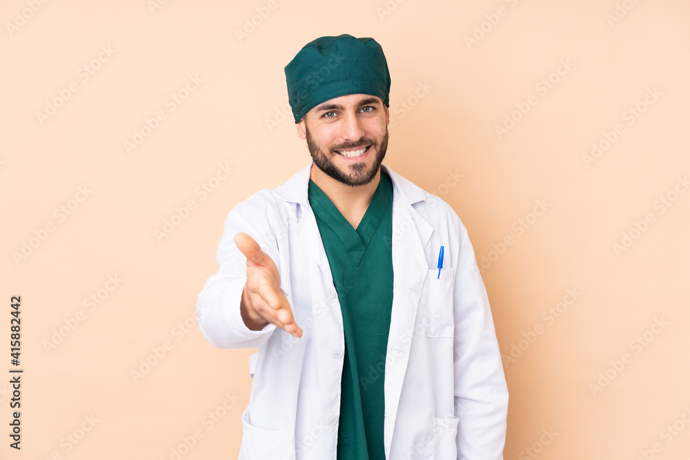 Surgeon man isolated on beige background handshaking after good deal Surgeon man isolated on beige background handshaking after good deal