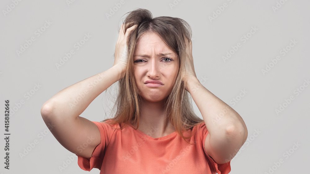 Portrait of young blond woman in panic grabbing her head in fear or frustration. Stress and mental health Portrait of young blond woman in panic grabbing her head in fear or frustration. Stress and mental health
