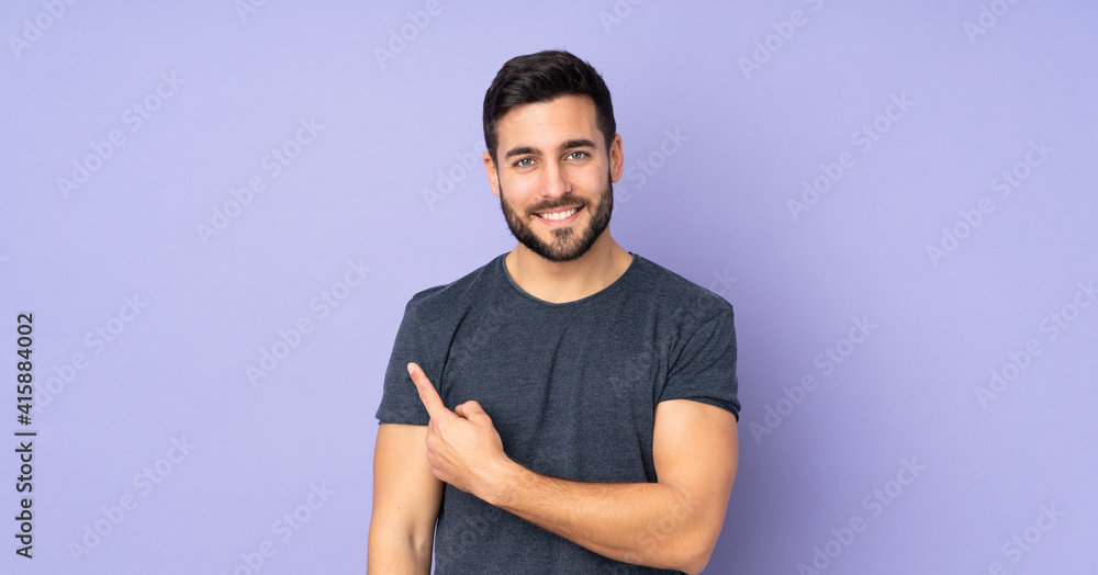 Caucasian handsome man pointing to the side to present a product over isolated purple background Caucasian handsome man pointing to the side to present a product over isolated purple background