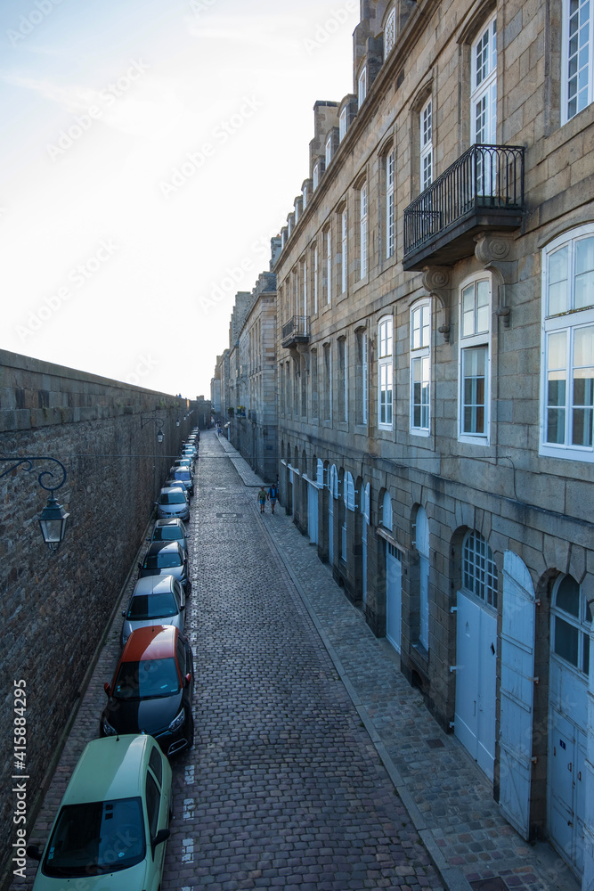 Saint-Malo, France - August 25, 2019: Historic wall and narrow street with parked cars in Intra Muros of the old town of Saint Malo, Brittany, France