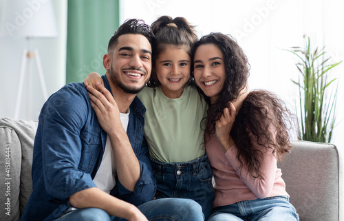 Happy Family Portrait. Smiling arabic parents and their little daughter posing together photo