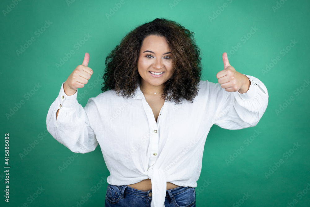 Young african american girl wearing white shirt over green background success sign doing positive gesture with hand, thumbs up smiling and happy. cheerful expression Young african american girl wearing white shirt over green background success sign doing positive gesture with hand, thumbs up smiling and happy. cheerful expression