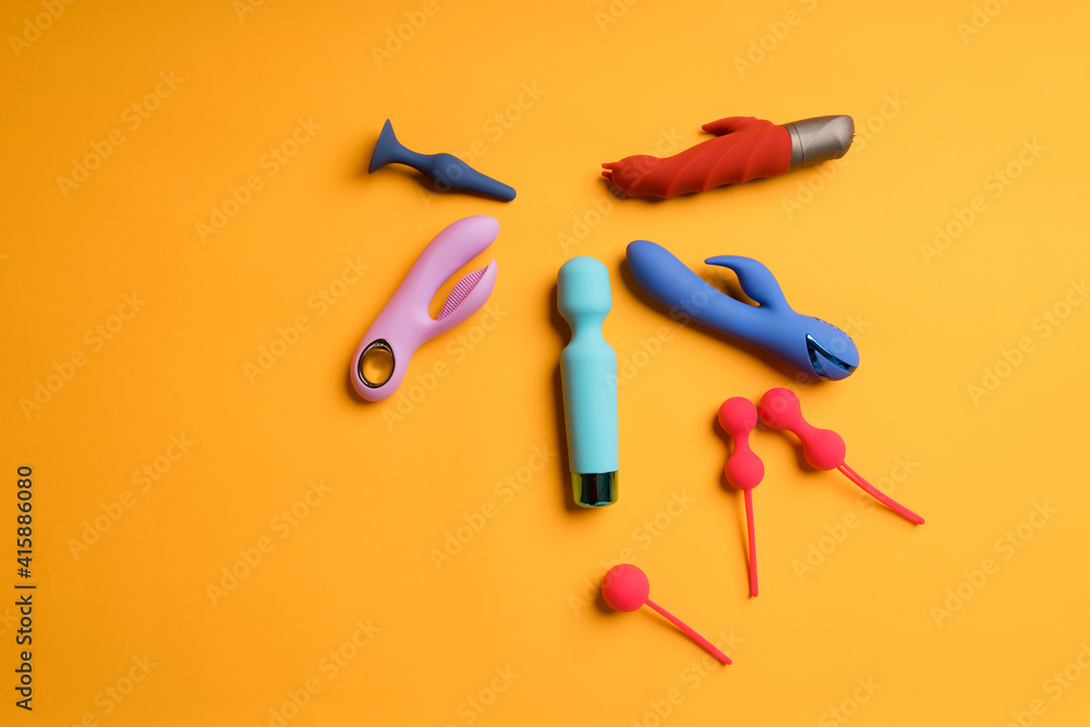 An abundance of multi-colored dildos and kegel balls on a yellow background. Clitoris massager, sex toys to maintain women's health. Space for text An abundance of multi-colored dildos and kegel balls on a yellow background. Clitoris massager, sex toys to maintain women's health. Space for text