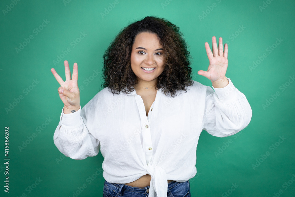 Young african american girl wearing white shirt over green background showing and pointing up with fingers number eight while smiling confident and happy Young african american girl wearing white shirt over green background showing and pointing up with fingers number eight while smiling confident and happy
