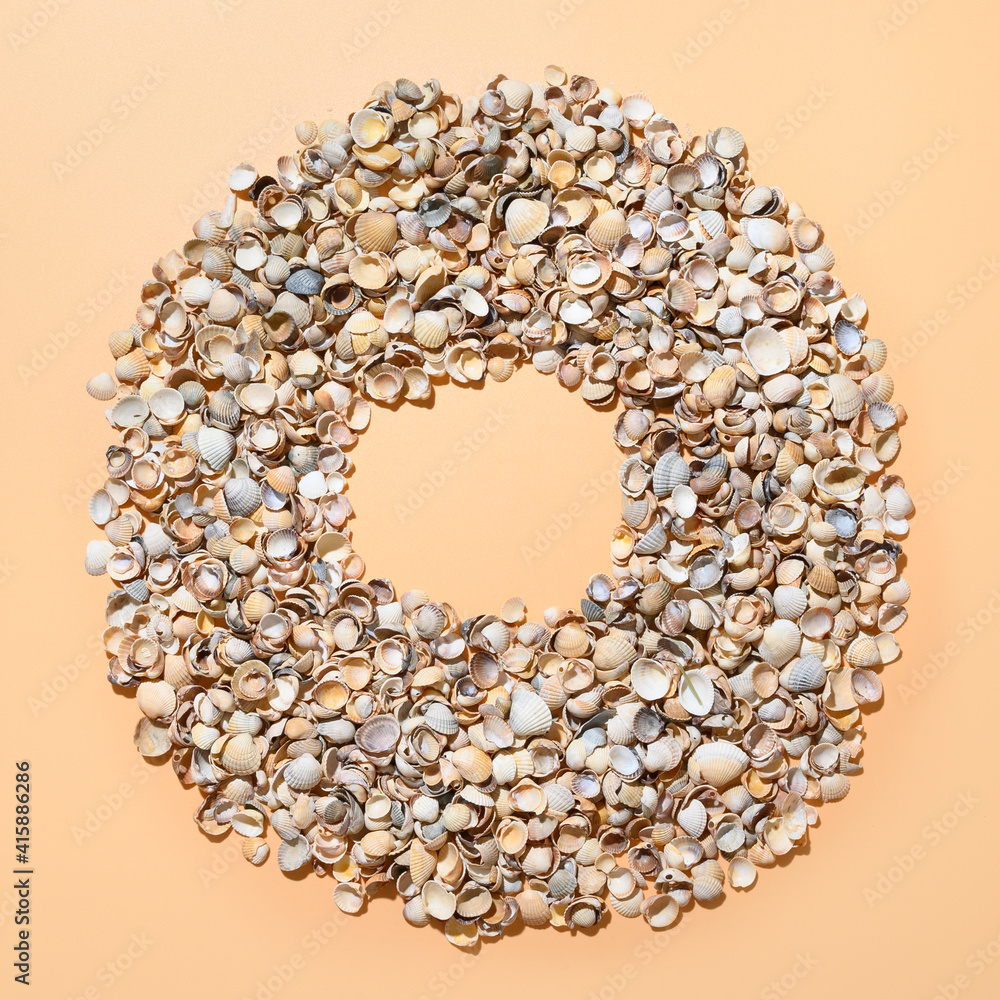 Obraz premium Seashells as wreath with copy space on beige background. View from above.