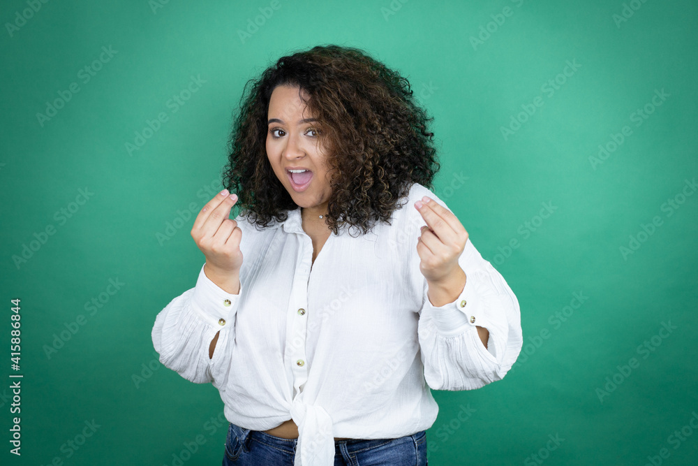 Young african american girl wearing white shirt over green background doing money gesture with hands, asking for salary payment, millionaire business Young african american girl wearing white shirt over green background doing money gesture with hands, asking for salary payment, millionaire business
