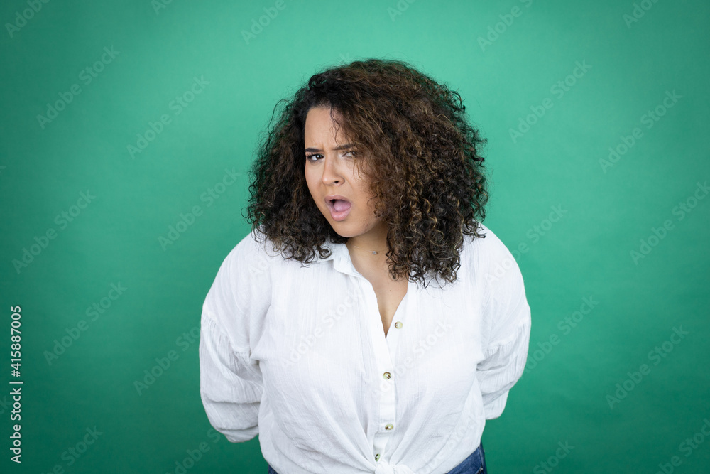 Young african american girl wearing white shirt over green background afraid and shocked with surprise and amazed expression, fear and excited face.