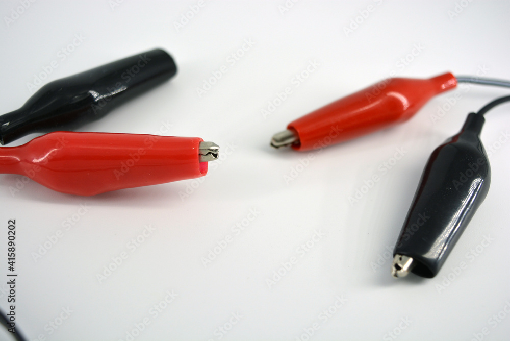 Black wire with red and black insulation, rubber and metal crocodiles for lining to the wire located on a white background. Black wire with red and black insulation, rubber and metal crocodiles for lining to the wire located on a white background.