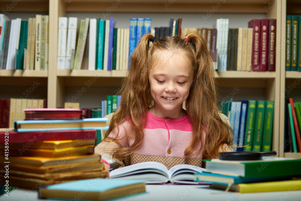 school girl reading book while preparing for lesson in library, diligent and shy child is concentrated on reading school girl reading book while preparing for lesson in library, diligent and shy child is concentrated on reading