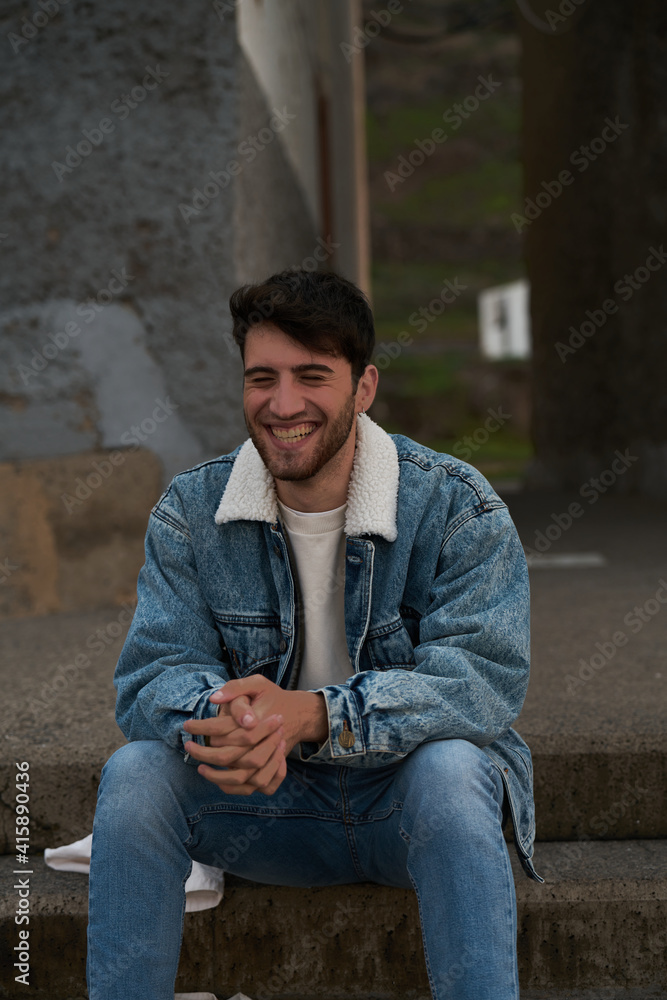 handsome student sitting in an urban setting on a beach in gran canaria late in the day at sunset handsome student sitting in an urban setting on a beach in gran canaria late in the day at sunset