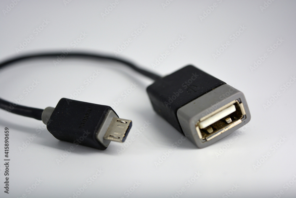 Adapter black wire for computer and phone is located on a white plastic background. Adapter black wire for computer and phone is located on a white plastic background.