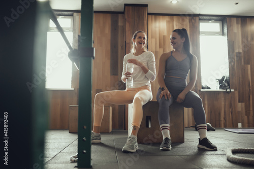 Two girls train in the gym. One girl teaches a friend and helps her with training.