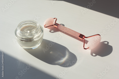 Obraz na płótnie Concept of minimalist skincare routine (skinimalism). Closeup of moisturizer and rose quartz roller with contrasting shadows. w salonie