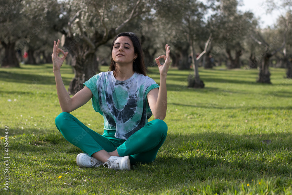 Woman meditating in the park wearing colorful clothes