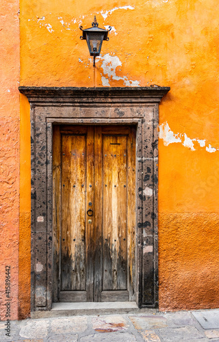 Old faded door with a stone frame and an orange pealing wall