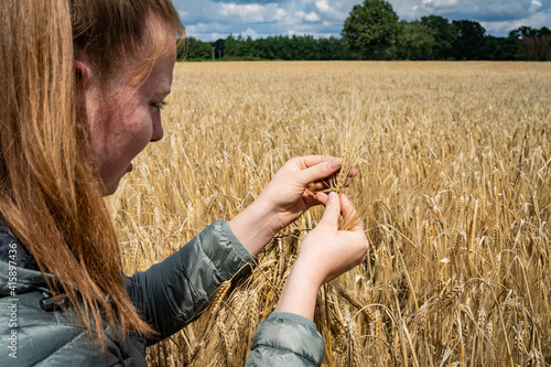 Ackerbau - junge Frau kontrolliert die Reifeentwicklung von Getreideähren, landwirtschaftliches Symbolfoto. photo