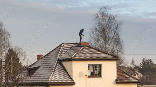 Photo A chimney sweep cleans the chimney on the roof of a detached house