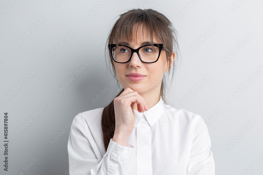Portrait of a young woman thinking over an idea. Pensive student with glasses.