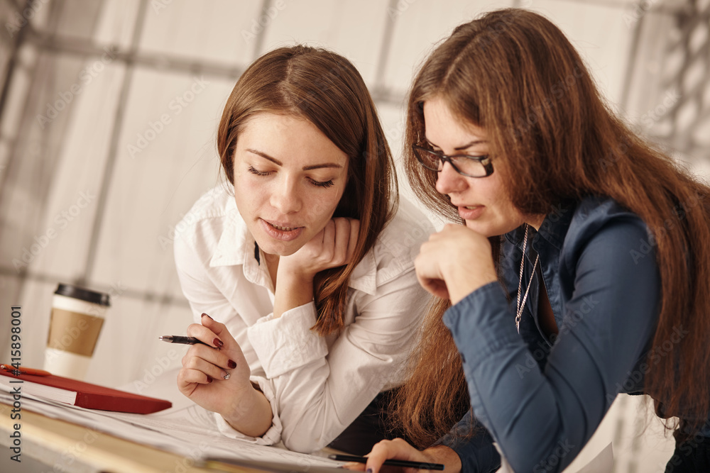 Close up Two Happy Young Businesswomen at the Office Talking About Business Report on Paper. Close up Two Happy Young Businesswomen at the Office Talking About Business Report on Paper.