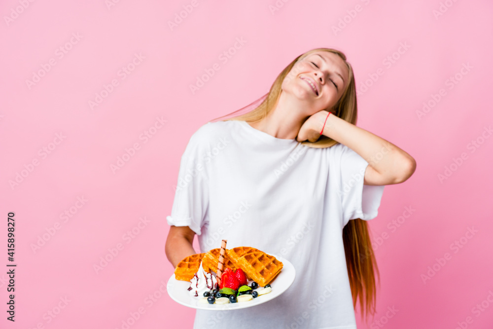 Young russian woman eating a waffle isolated dancing and having fun.