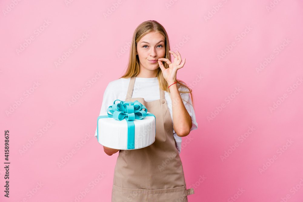 Young russian baker woman holding a delicious cake with fingers on lips keeping a secret. Young russian baker woman holding a delicious cake with fingers on lips keeping a secret.