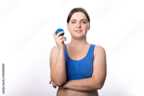 A girl with a smile holds a ball for myofascial points in her hand. healthy lifestyle. Suitable for sports massage roller. White background. place for text. 