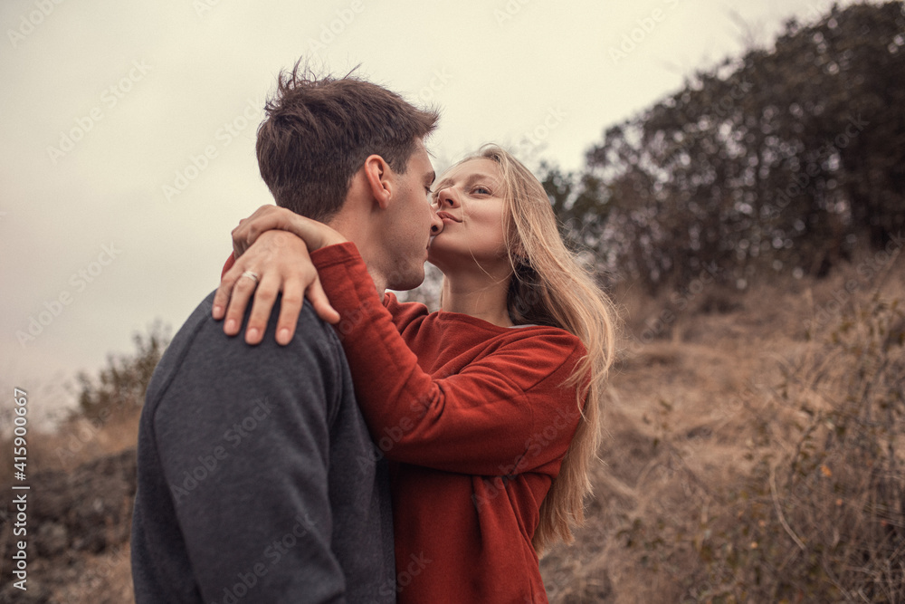 A couple of lovers cuddle in nature, a blonde girl with chic hair in an orange sweater, a fellow brunette in a gray sweater A couple of lovers cuddle in nature, a blonde girl with chic hair in an orange sweater, a fellow brunette in a gray sweater