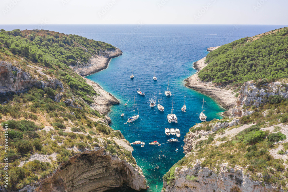 Aerial shot of yachts boats at Stiniva cove beach of Adriatic sea on Vis Island in Croatia summer
