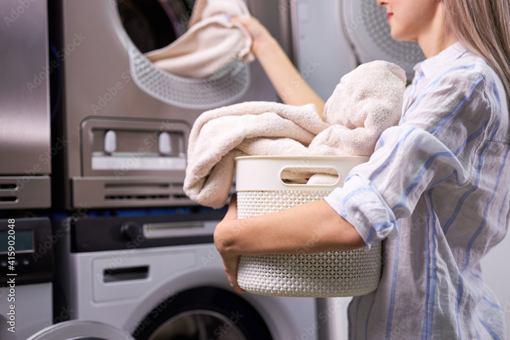 woman doing laundry - putting out white garments from washing machine, putting it in basket, basin. in washing house woman doing laundry - putting out white garments from washing machine, putting it in basket, basin. in washing house