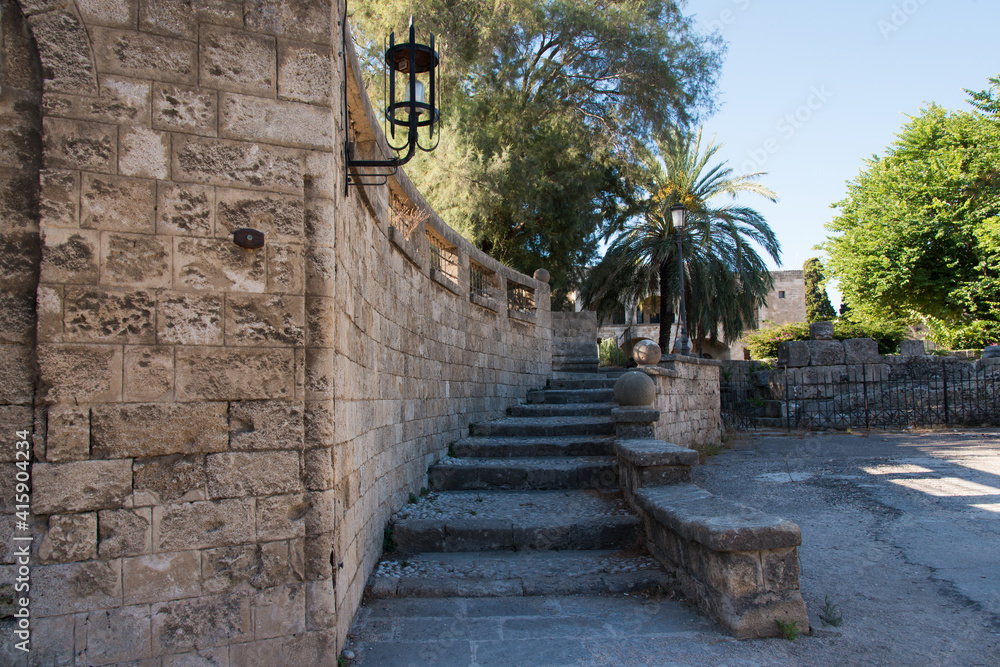 Beautiful ancient stairs at Rhodes town fortification. Palm tree and metal lamp. Rhodes, Dodecanese, Greece.