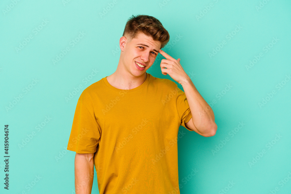 Young caucasian man isolated on blue background showing a disappointment gesture with forefinger. Young caucasian man isolated on blue background showing a disappointment gesture with forefinger.