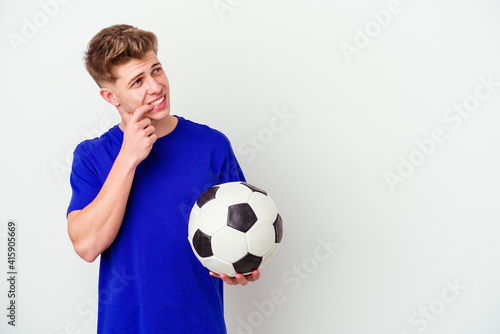 Young caucasian man playing soccer isolated on background relaxed thinking about something looking at a copy space.