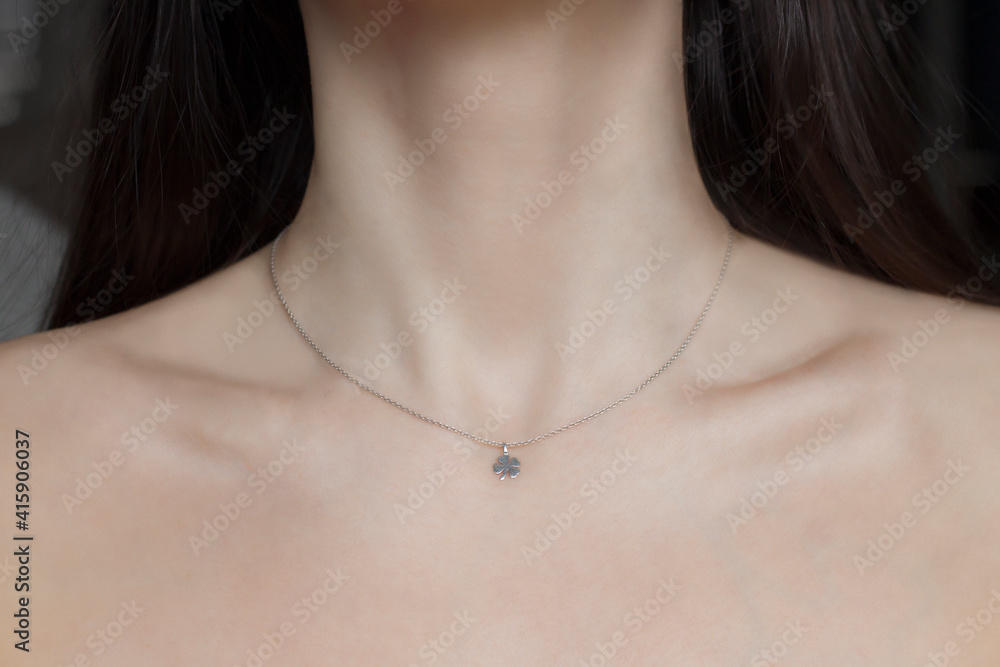 Woman neck and chin. Silver necklace with trefoil pendant