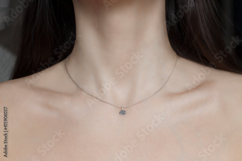 Woman neck and chin. Silver necklace with trefoil pendant