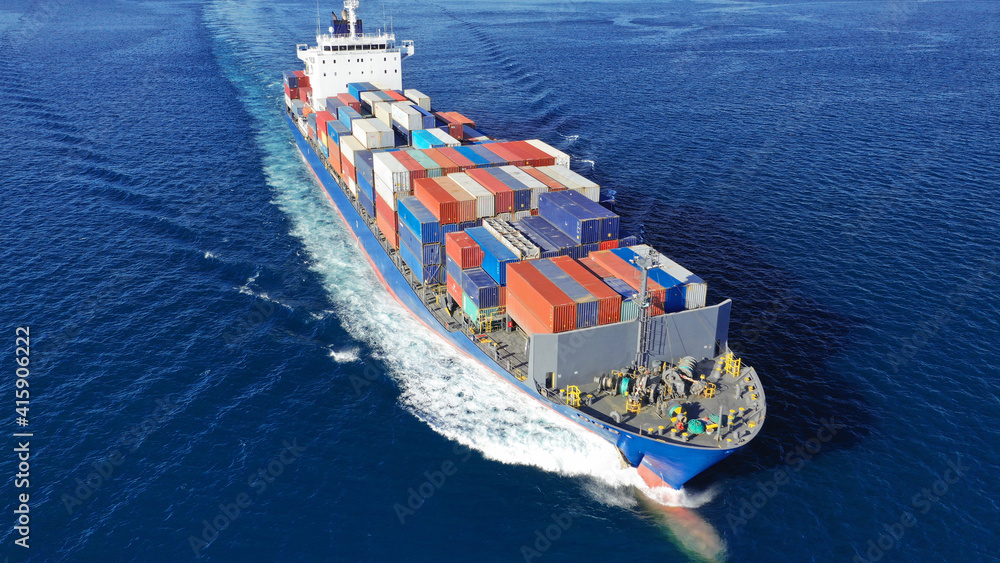 Fototapeta premium Aerial drone photo of colourful truck size container tanker ship cruising deep blue sea near commercial port of Piraeus, Attica, Greece