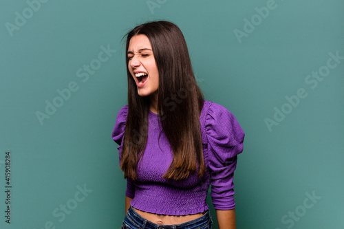 Young Indian woman isolated on blue background shouting very angry, rage concept, frustrated.