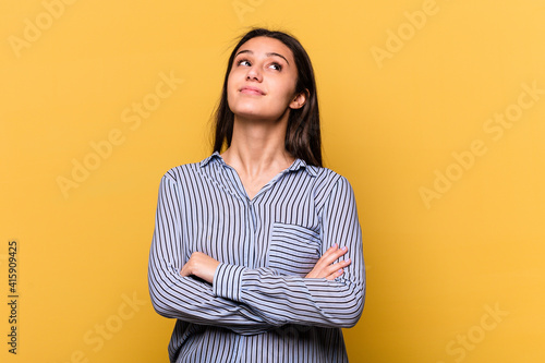 Young Indian woman isolated on yellow background dreaming of achieving goals and purposes © Asier
