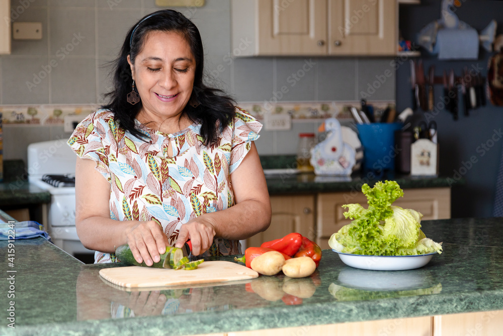 Smiling middle aged hispanic woman making fresh salad in her kitchen - lady in cooking healthy food with organic vegetables Smiling middle aged hispanic woman making fresh salad in her kitchen - lady in cooking healthy food with organic vegetables