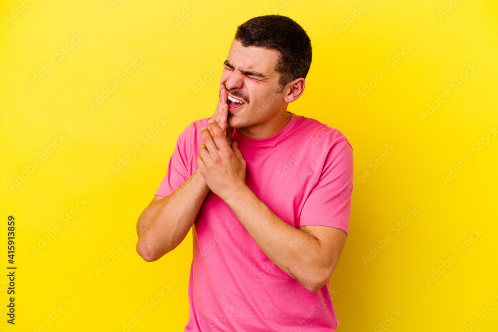 Young caucasian cool man isolated on yellow background having a strong teeth pain, molar ache. Young caucasian cool man isolated on yellow background having a strong teeth pain, molar ache.