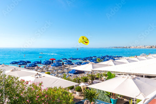 A happy smiley face parachute parasailer takes off from a beach resort at the Promenade on the French Riviera in Nice, France. photo