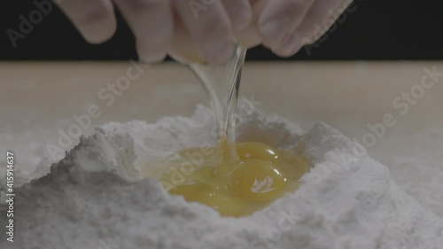 A third egg is cracked into flour bowl
