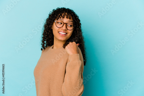 Young african american afro woman isolated points with thumb finger away, laughing and carefree.