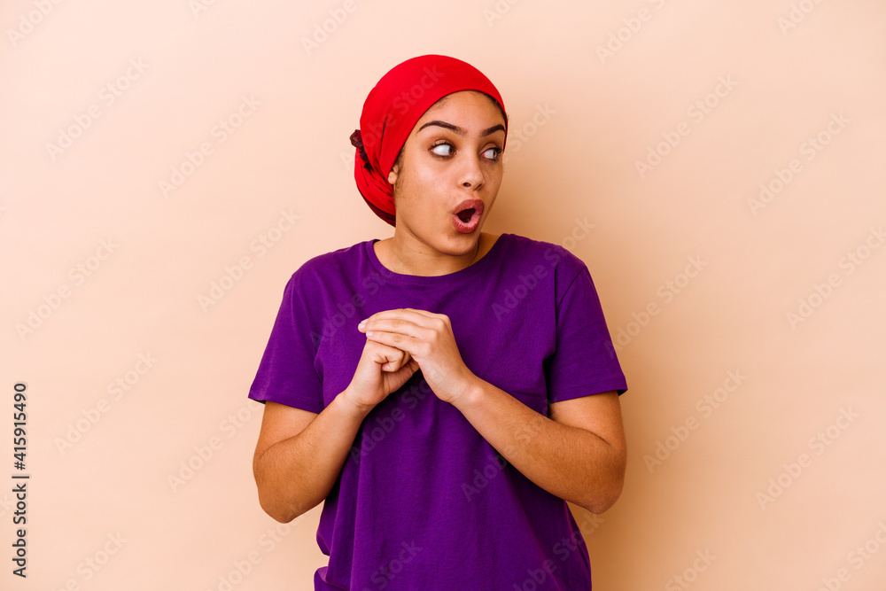 Young african american woman isolated on beige background praying for luck, amazed and opening mouth looking to front.