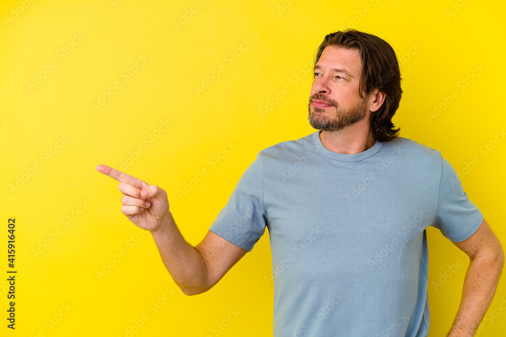 Middle age caucasian man isolated on yellow background smiling cheerfully pointing with forefinger away. Middle age caucasian man isolated on yellow background smiling cheerfully pointing with forefinger away.