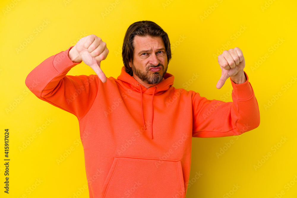 Middle age caucasian man isolated on yellow background showing a dislike gesture, thumbs down. Disagreement concept. Middle age caucasian man isolated on yellow background showing a dislike gesture, thumbs down. Disagreement concept.