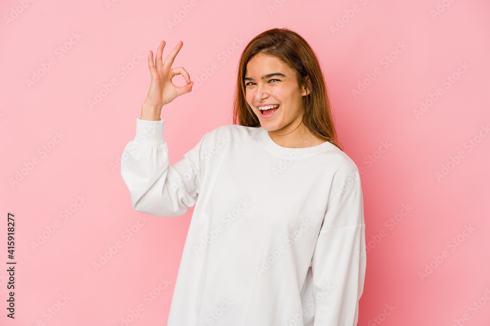 Young skinny caucasian teenager girl winks an eye and holds an okay gesture with hand. Young skinny caucasian teenager girl winks an eye and holds an okay gesture with hand.