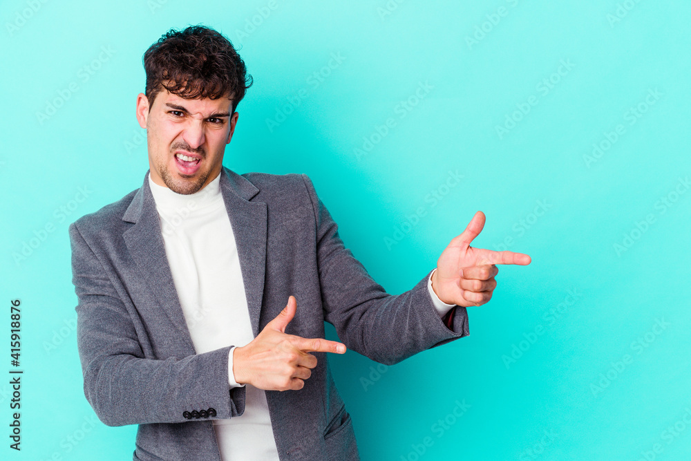 Young caucasian man isolated on blue background pointing with forefingers to a copy space, expressing excitement and desire. Young caucasian man isolated on blue background pointing with forefingers to a copy space, expressing excitement and desire.